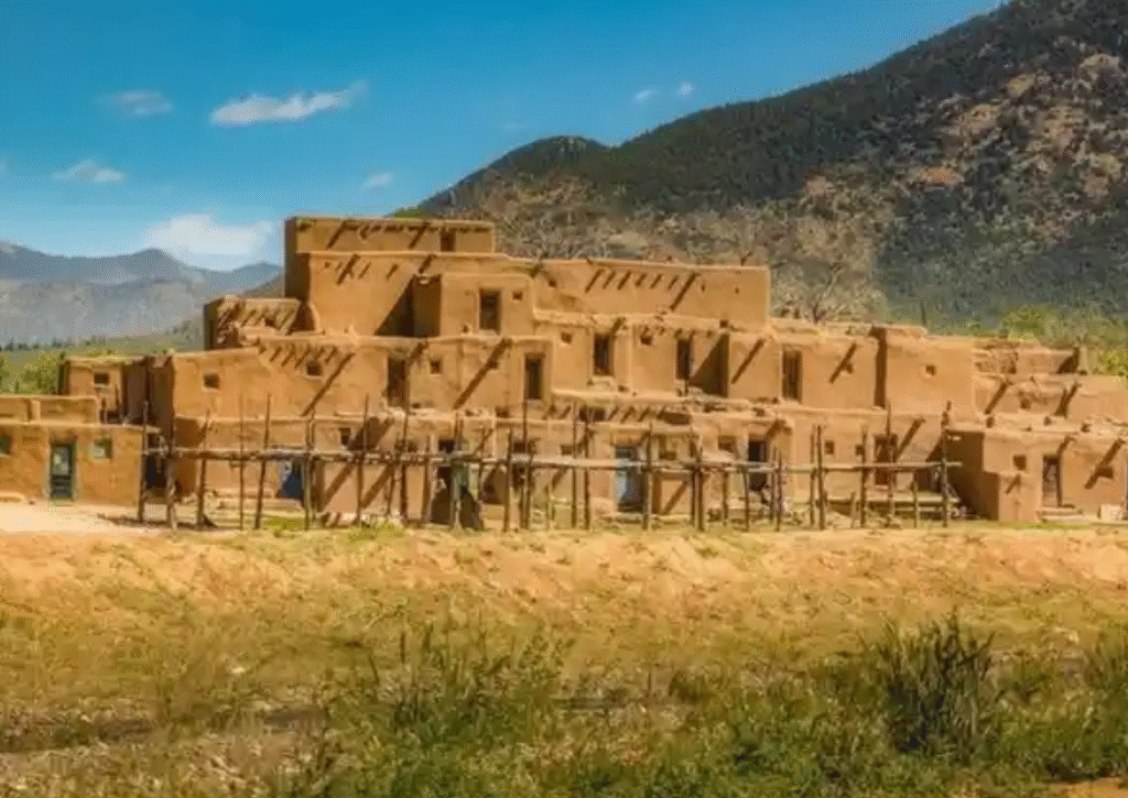 Ancient adobe buildings of Taos Pueblo with mountains in the background