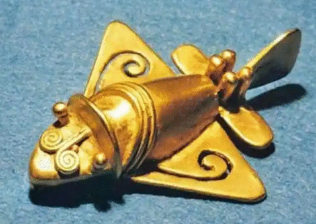 Gold artifact resembling an airplane with triangular wings and spiral decorations