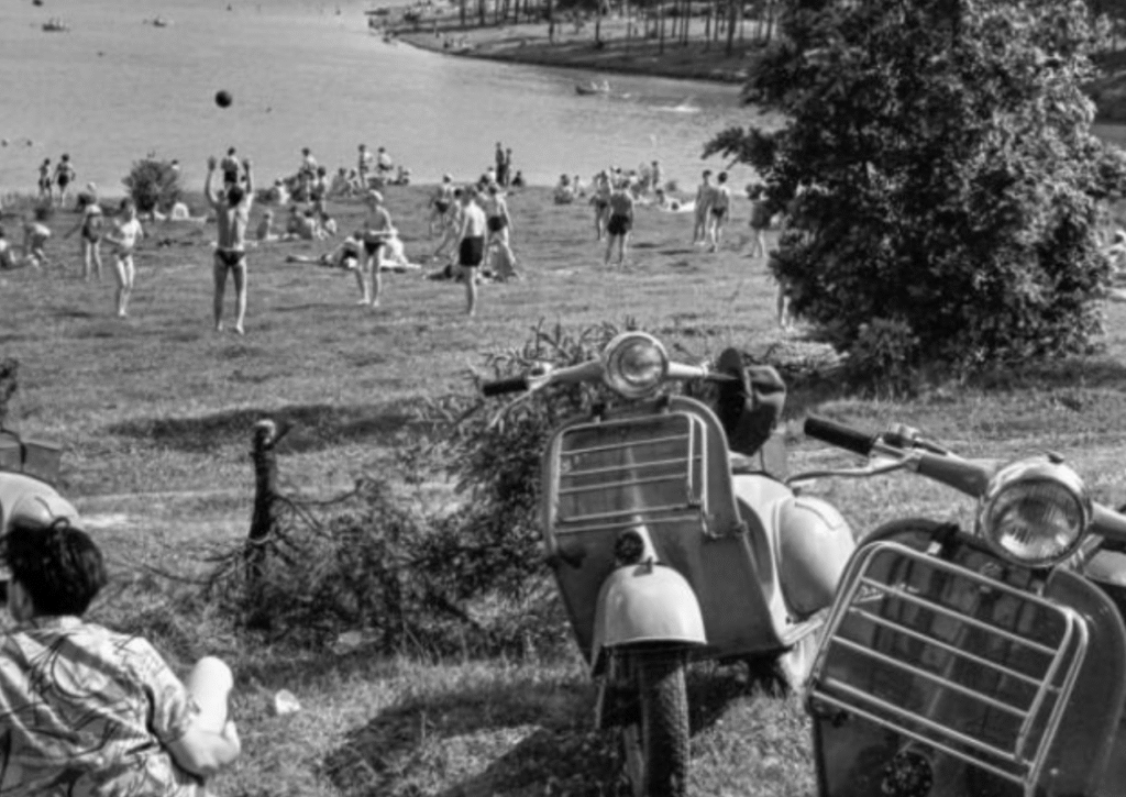 People playing volleyball with parked mopeds nearby